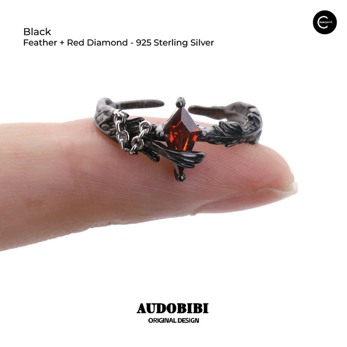 A Part Of Me black feather and red diamond 925 sterling silver ring shown on a finger