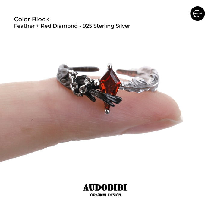 A Part Of Me 925 sterling silver ring with feather and red diamond detail, shown on a finger.