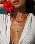 Red bead necklace layered with a pearl necklace and a gold chain