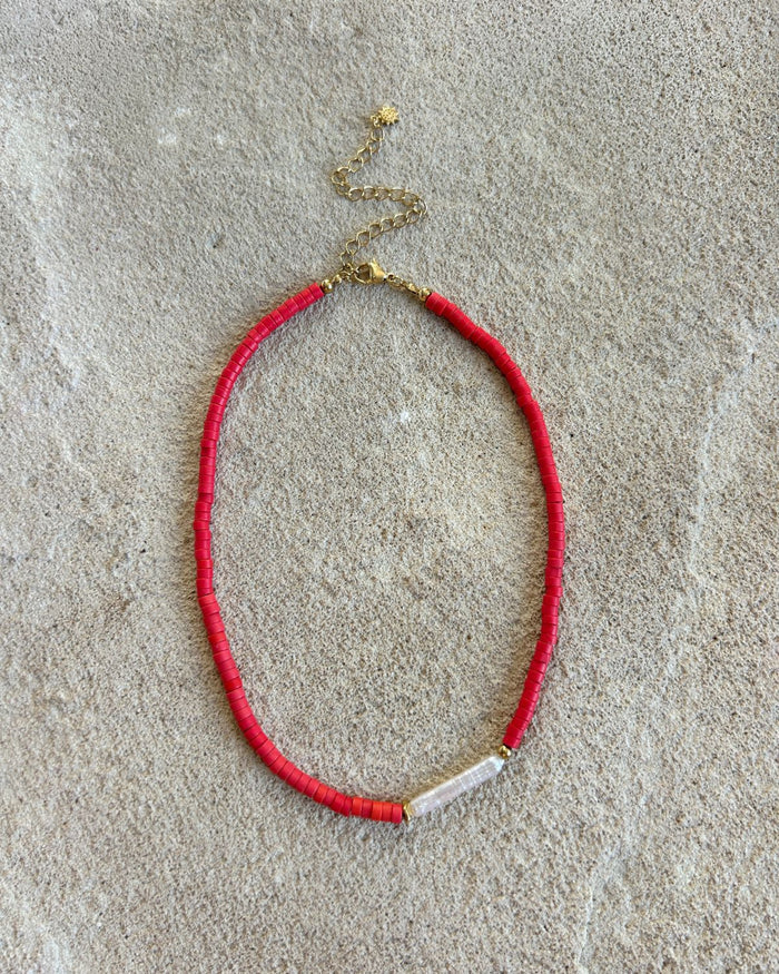 red beaded necklace on a stone surface