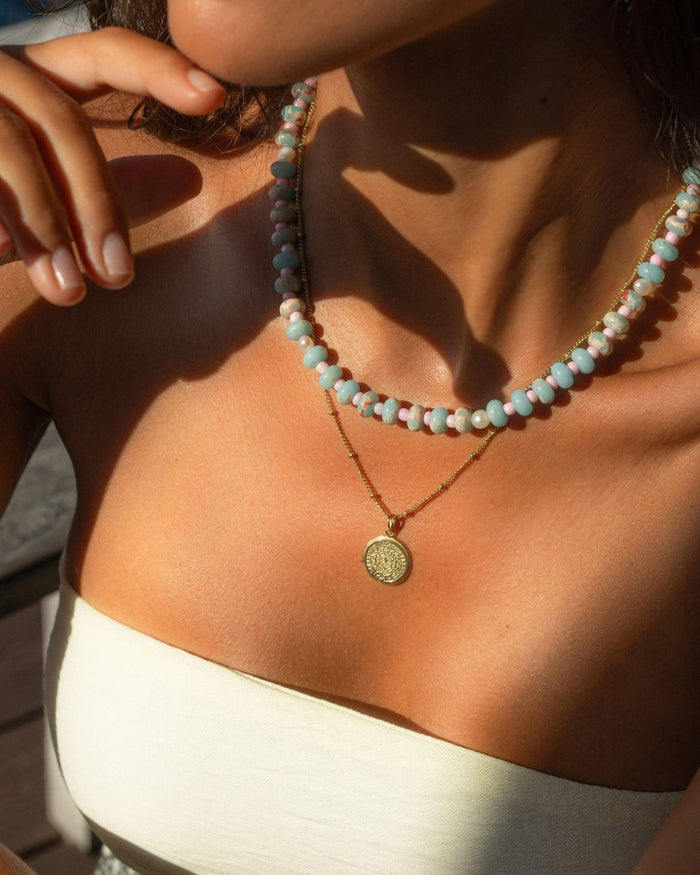 colorful beaded necklace layerd with a gold pendant on a model