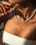 colorful beaded necklace layerd with a gold pendant on a model