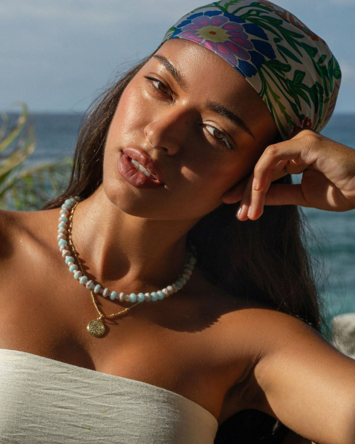 Colorful beaded necklace worn by a woman in a floral summer headscarf