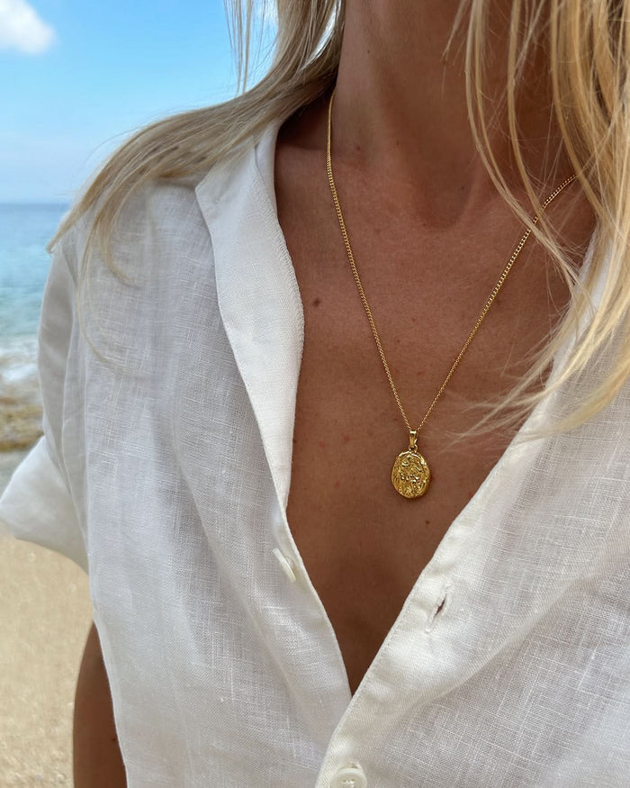 a woman wearing white shirt and gold pendant necklace
