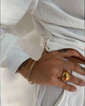 hand featuring a Cuban bracelet and large dome ring