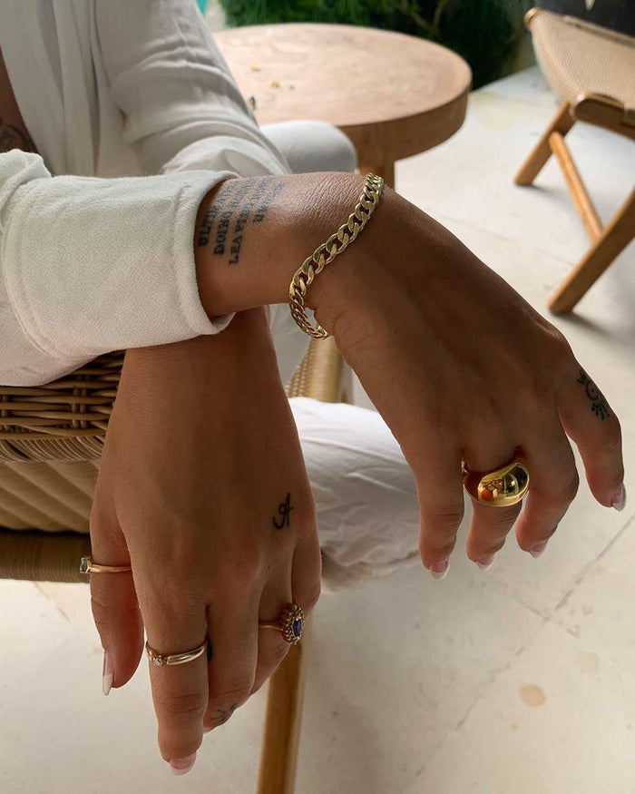 hands featuring gold rings and a Cuban chain bracelet