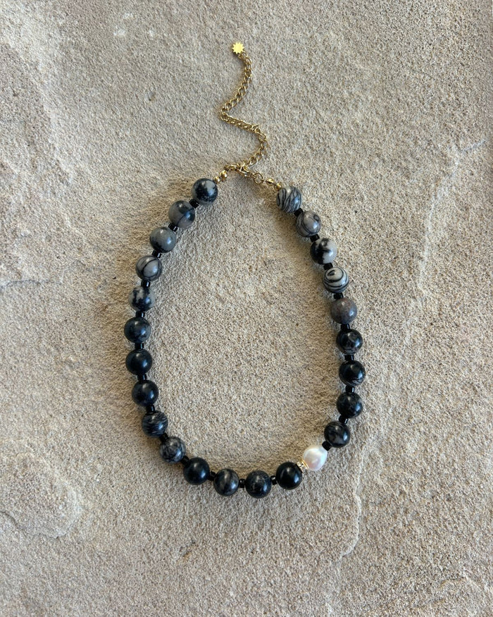 black beaded necklace on a stone surface