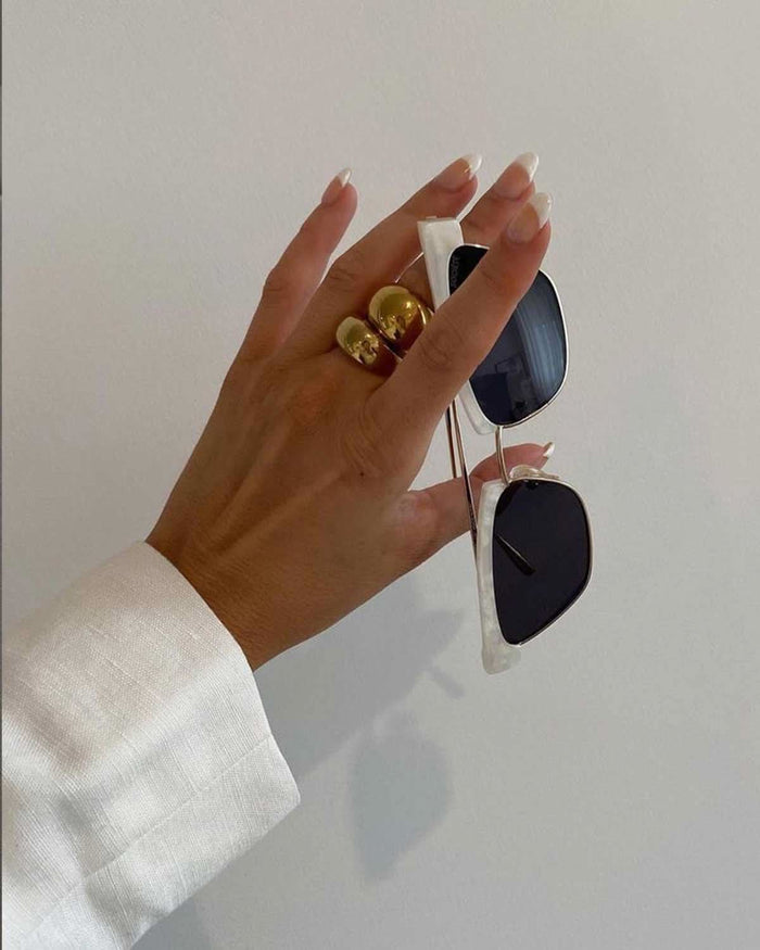 hand holding sunnies wearing gold rings