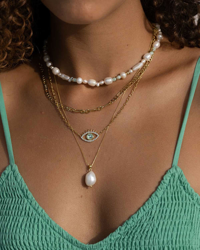 mint top styled with Cult of Sun set of gold, evil eye, and pearl necklaces