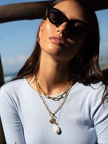 model wearing clear color long-sleeve with layers of necklaces