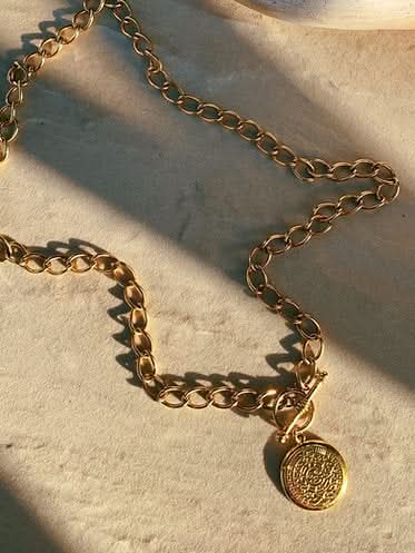 gold chain necklace with an Aztec calendar pendant