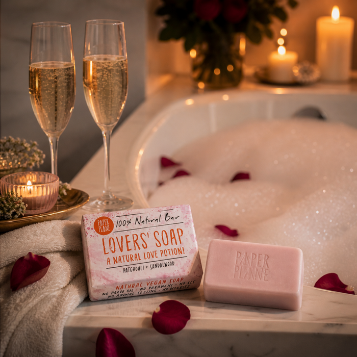 Paper Plane Lovers' Soap beside bubble bath with champagne glasses and candles