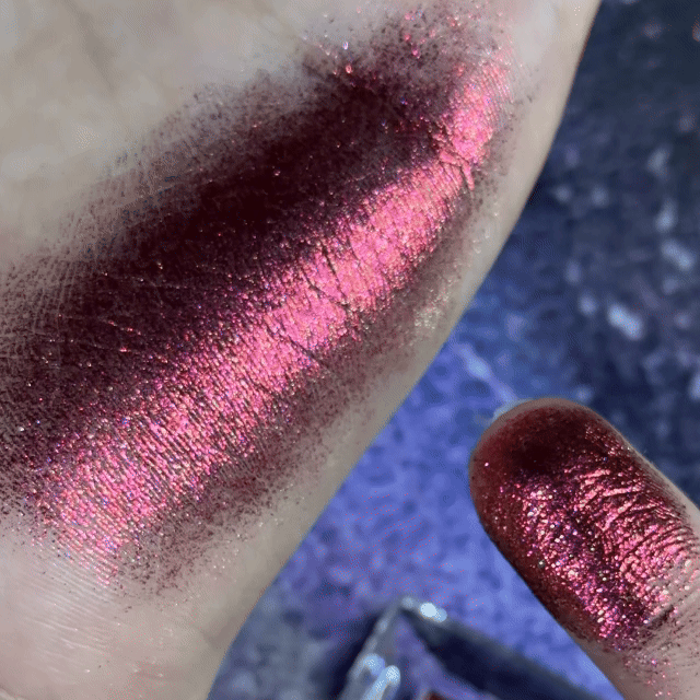 NOIRICORN Solar Flare single eyeshadow swatched on skin and fingertip in shimmering deep burgundy and pink