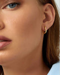face close up wearing a single small gold rectangle hoop
