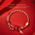 The Palace Museum Lucky Koi bracelet, braided multicolor cord with gold-tone charms, displayed on a red background