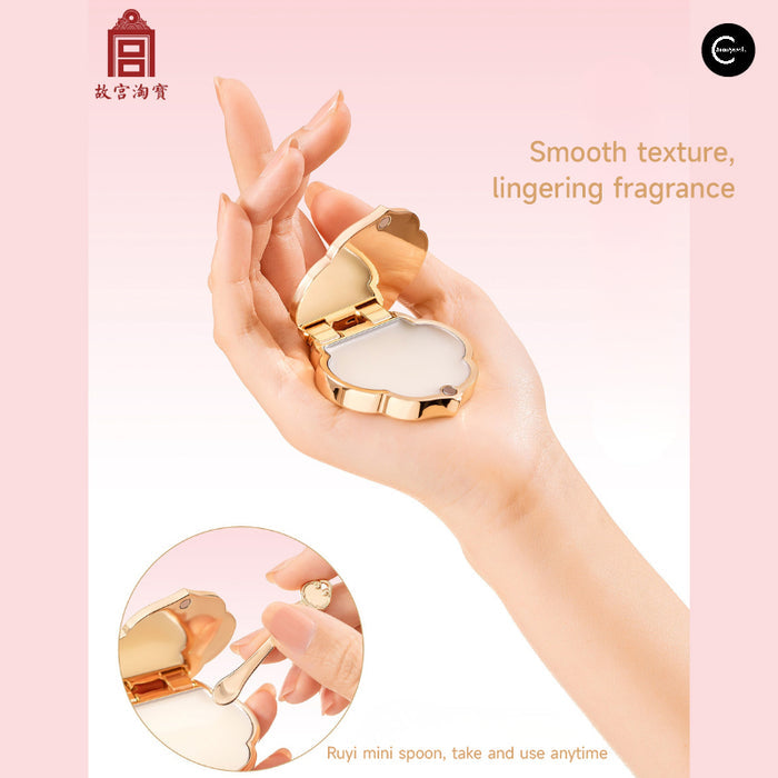 The Palace Museum Ruyi solid perfume balm compact open in a hand with a mini spoon
