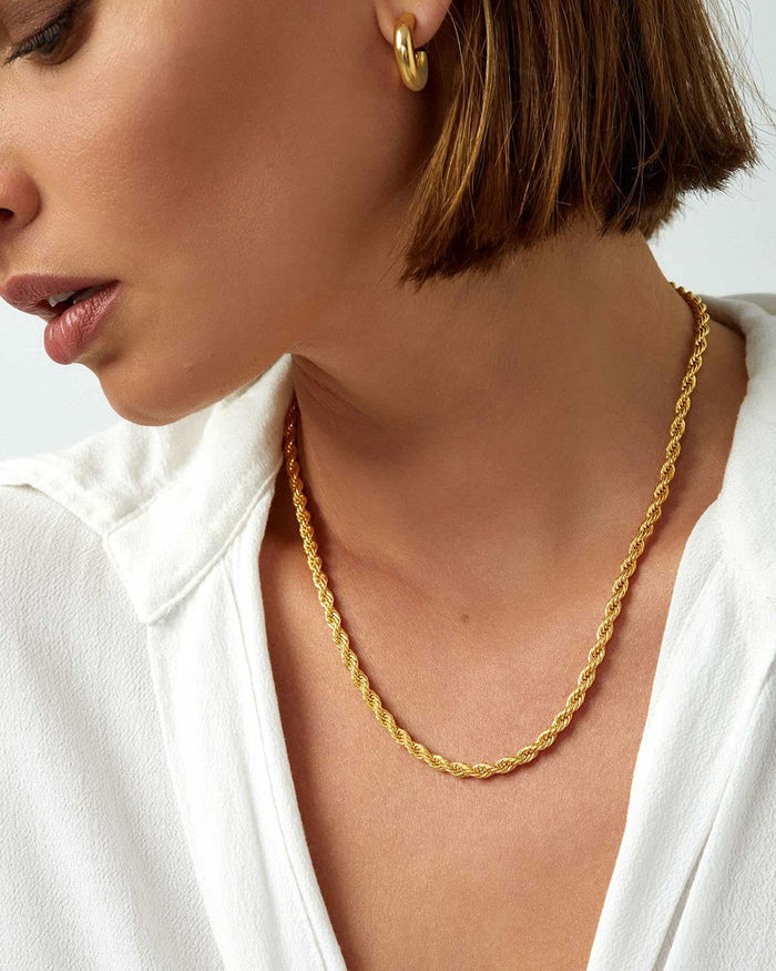 face and neck from the side featuring single gold necklace and earring