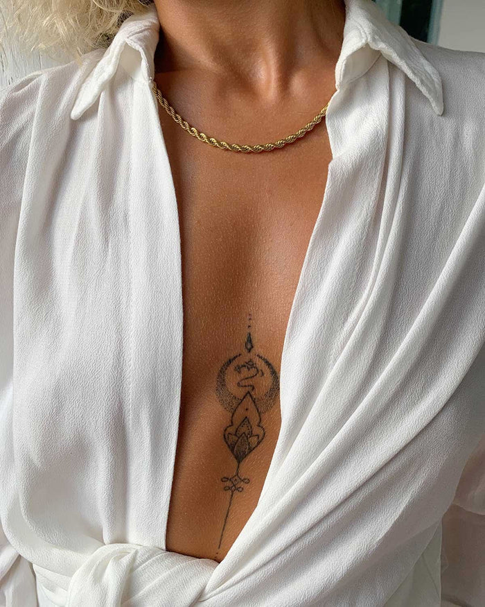 open white shirt showing tattoo and gold necklace